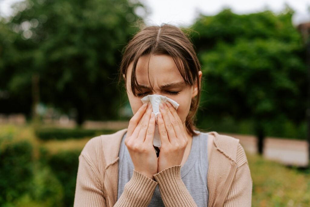 A woman blows her nose while suffering with hayfever, a potential cause of dry eyes