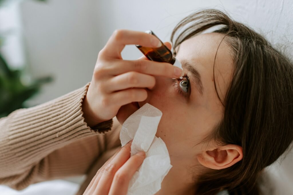 A woman administers eye drops at home