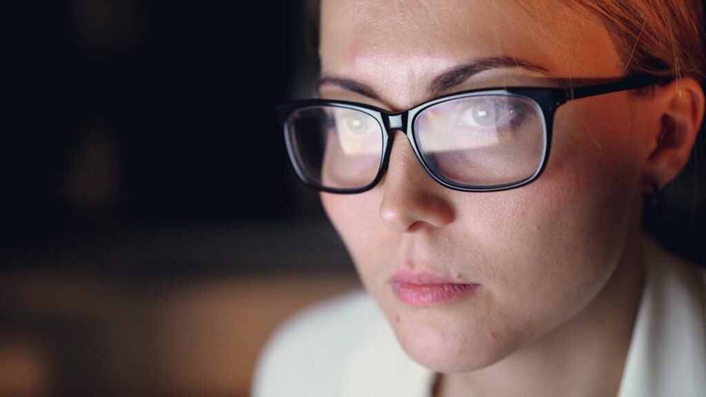 A woman with glasses staring at a computer screen, reflection in the glasses