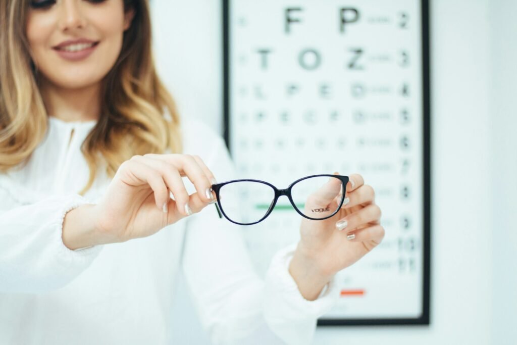 A woman holds a pair of glasses, about to try them on