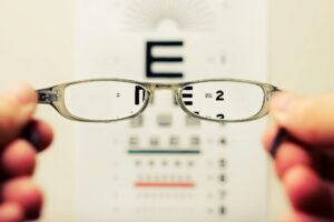 Holding up a pair of glasses to an eye exam letter sheet