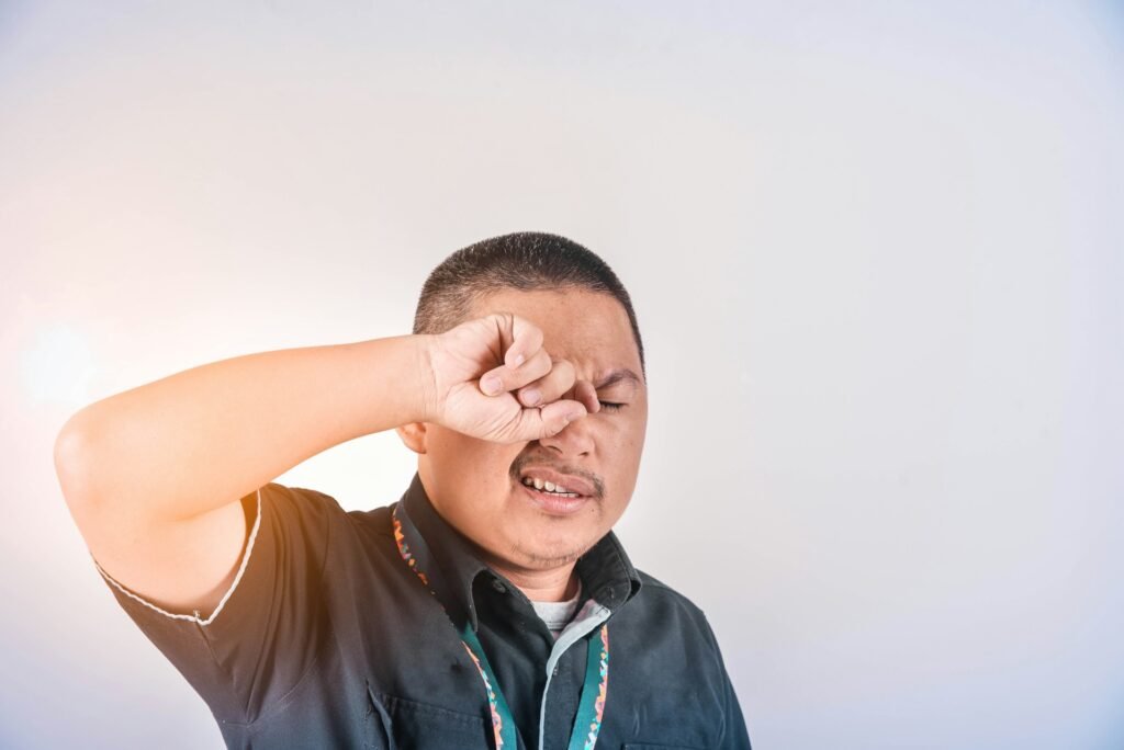 man rubs his eyes with blurry vision, suffering from astigmatism symptoms