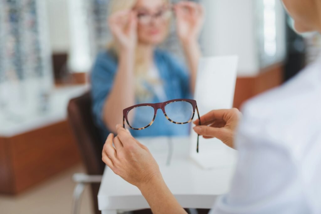 optometrist holds a pair of glasses up for a customer trying on new pairs