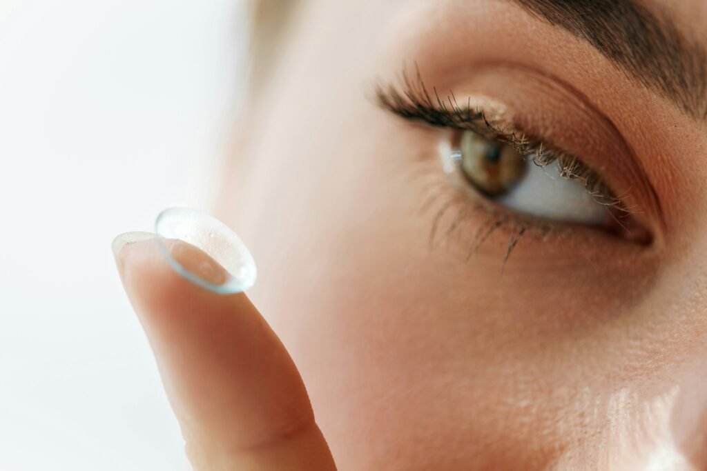 Close up of a woman holding a contact lens on her fingertip about to put it into her eye