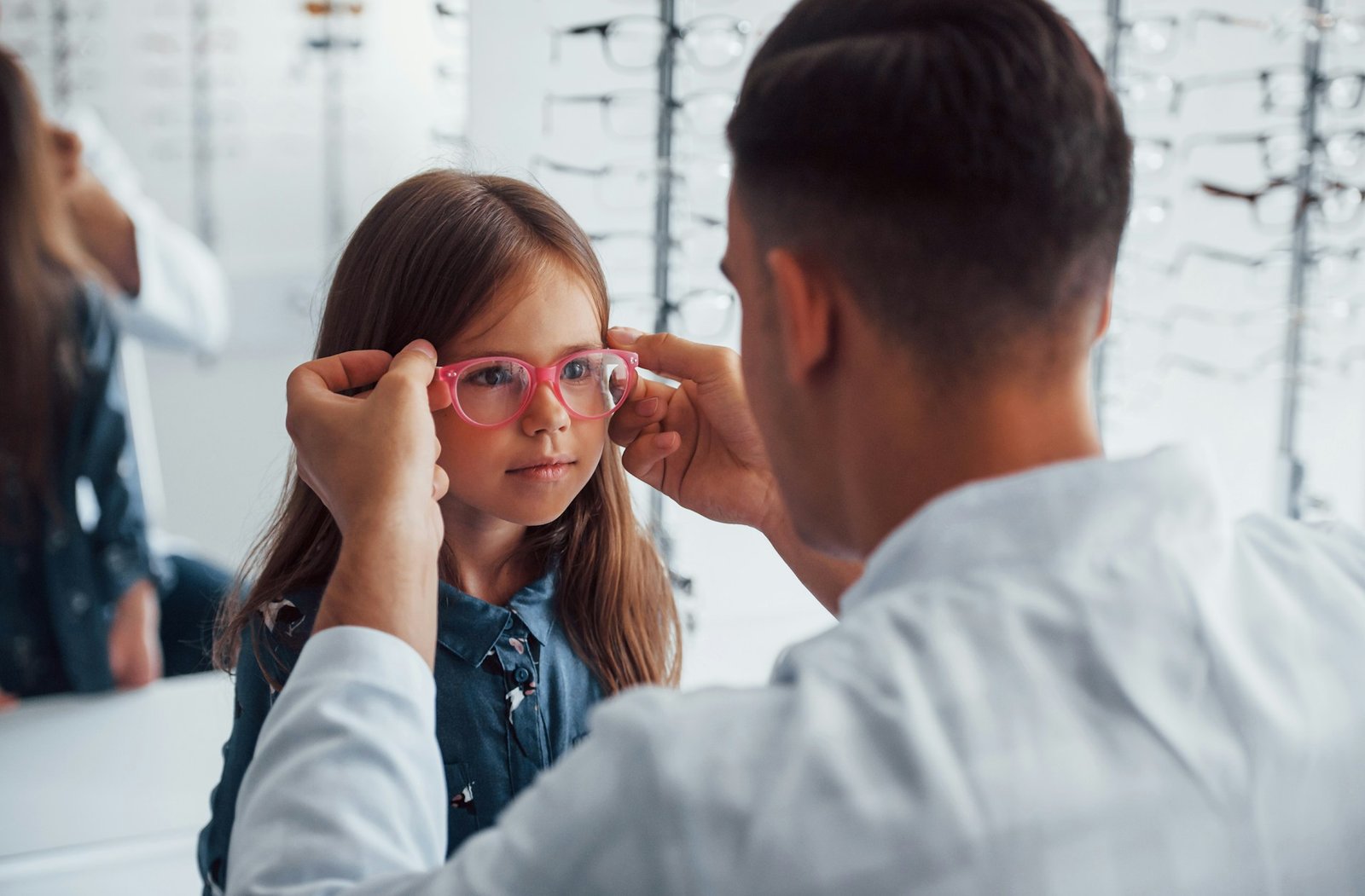 An optometrist examining a young child's eyes at their eye level